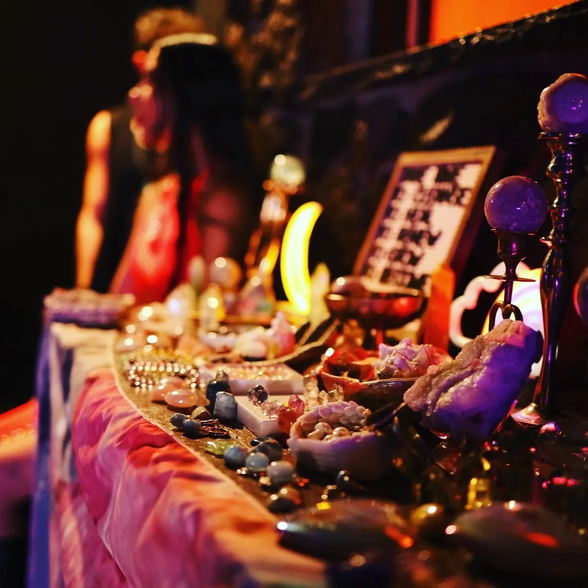 A vendor's table of crystals and curiosities lit by candlelight A vendor's table of crystals and curiosities lit by candlelight