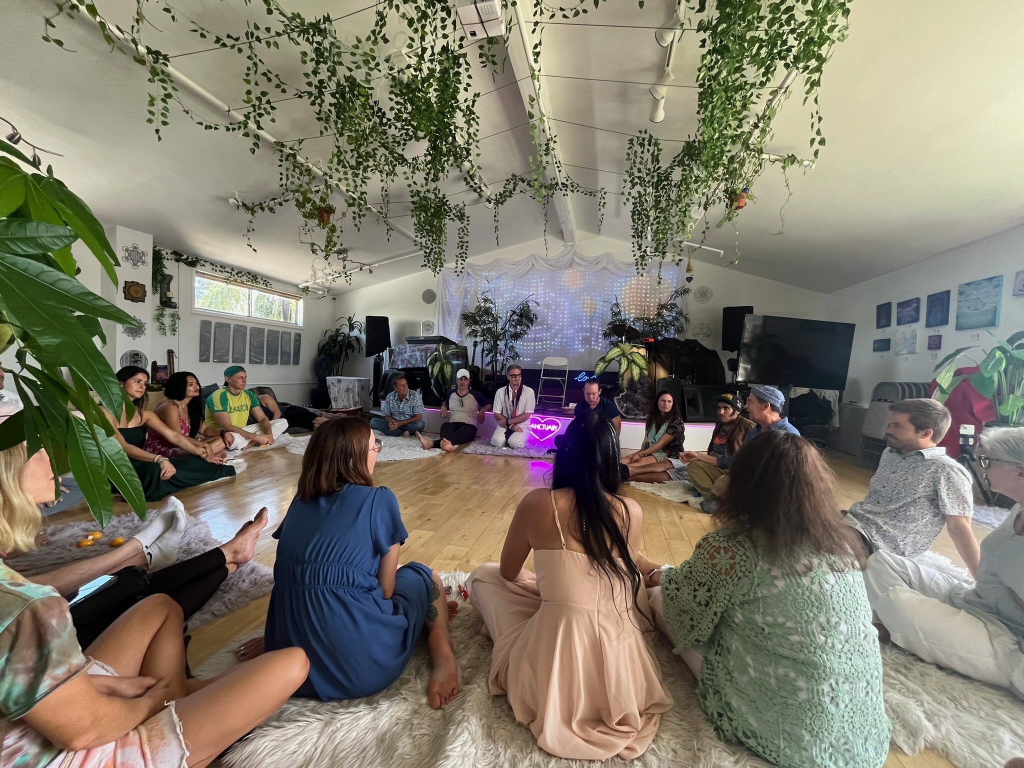 A Soul Sunday circle seated on sheepskins beneath hanging vines